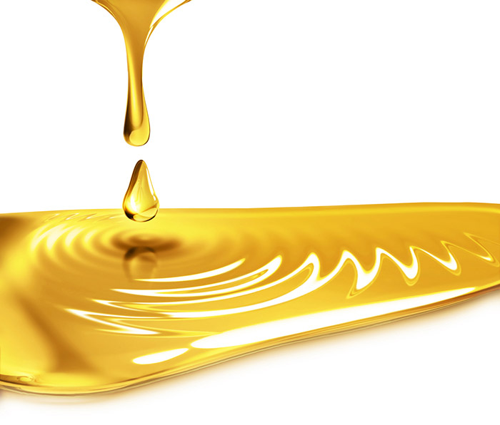 A small puddle of oil with additional oil dripping into it, causing ripples to form.