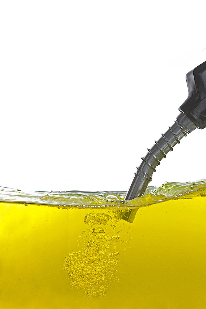 A large pool of oil with the nozzle of a petrol pump submerged in it.