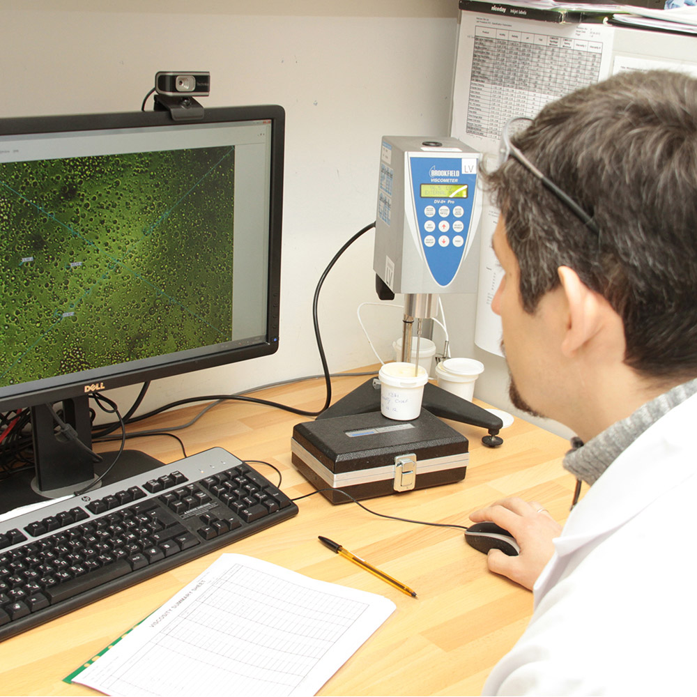 A scientist examines a computer screen displaying a zoomed-in view of cells.