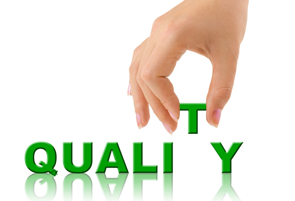 The word 'quality' in bold green letters is being reflected onto the ground, while a hand picks up the letter 'T'.