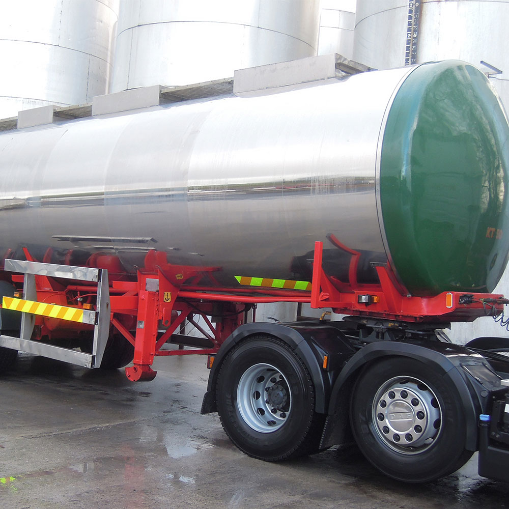 Side view of a shiny tank truck reflecting its surroundings on its polished surface.