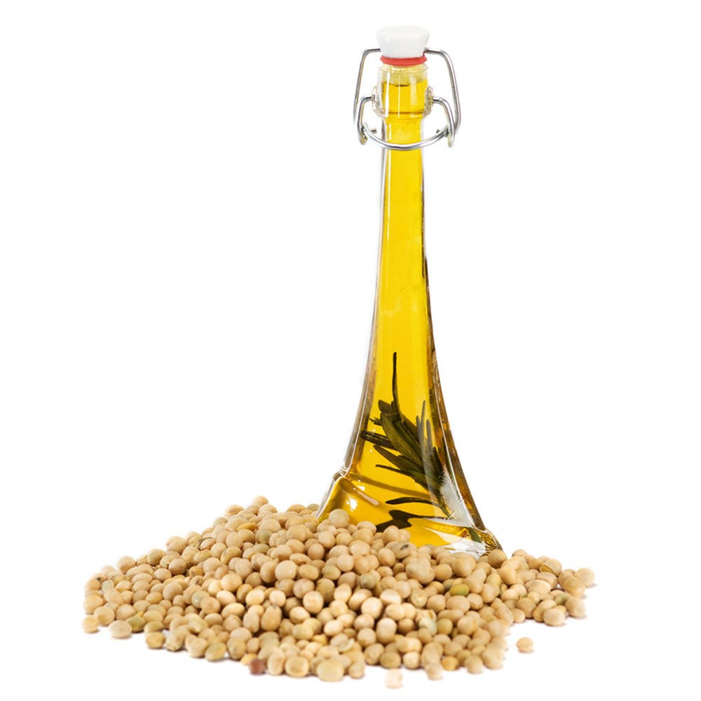 A tall, slim glass bottle of soya oil placed next to a pile of soya beans.