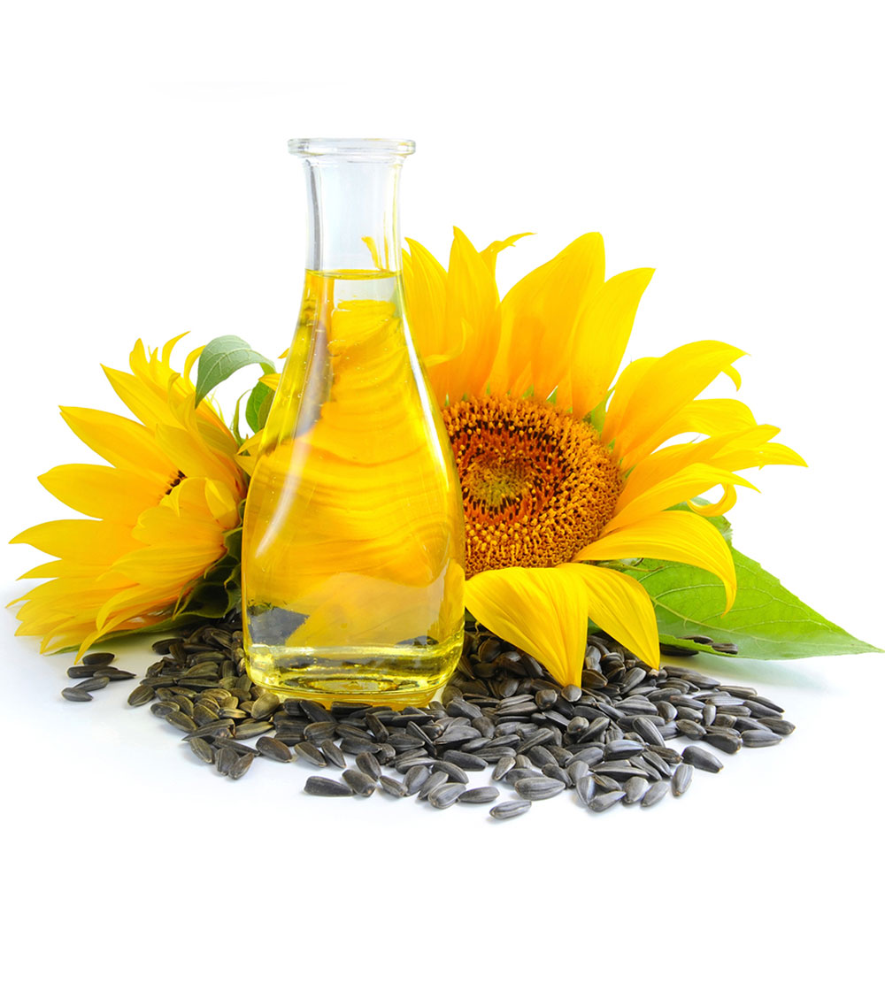 A glass bottle of sunflower oil positioned among sunflower seeds, with two large sunflower heads in the background.
